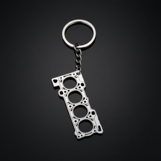 Metallic keychain shaped like a car engine block on a black background